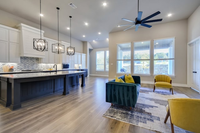 living room featuring light wood-type flooring, a wealth of natural light, and ceiling fan with notable chandelier