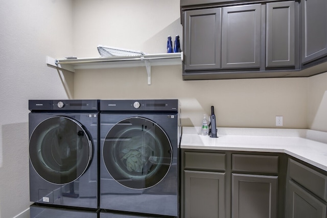 clothes washing area with cabinets and washing machine and clothes dryer