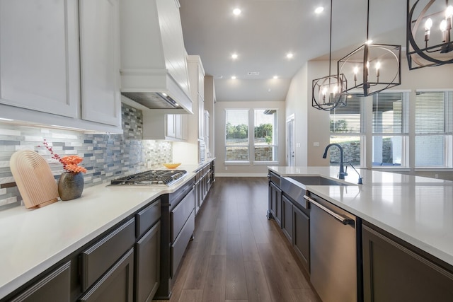 kitchen with stainless steel appliances, white cabinetry, sink, custom range hood, and dark hardwood / wood-style floors