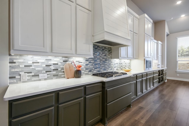 kitchen featuring white cabinetry, backsplash, custom range hood, dark hardwood / wood-style flooring, and stainless steel gas stovetop