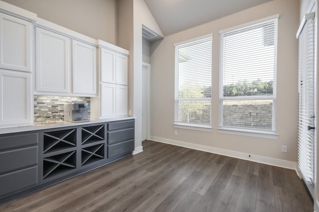 bar featuring dark hardwood / wood-style flooring, a wealth of natural light, lofted ceiling, and white cabinets