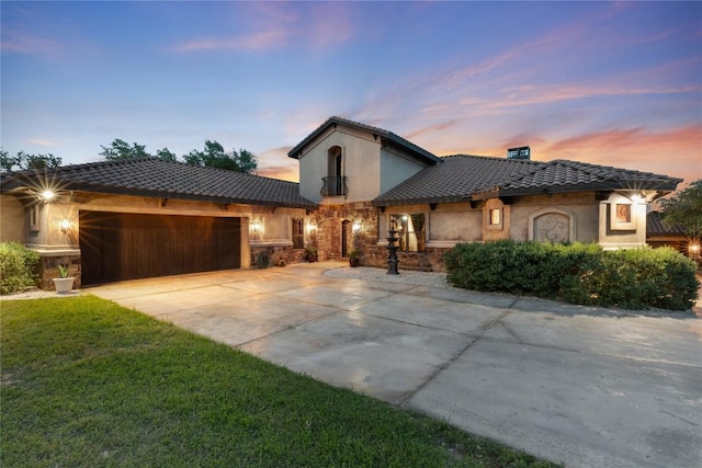 mediterranean / spanish house featuring a tile roof, stucco siding, an attached garage, stone siding, and driveway