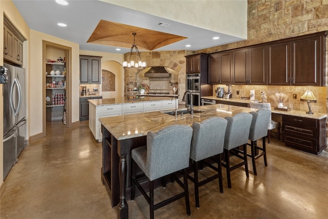 kitchen featuring sink, appliances with stainless steel finishes, decorative light fixtures, a large island, and decorative backsplash