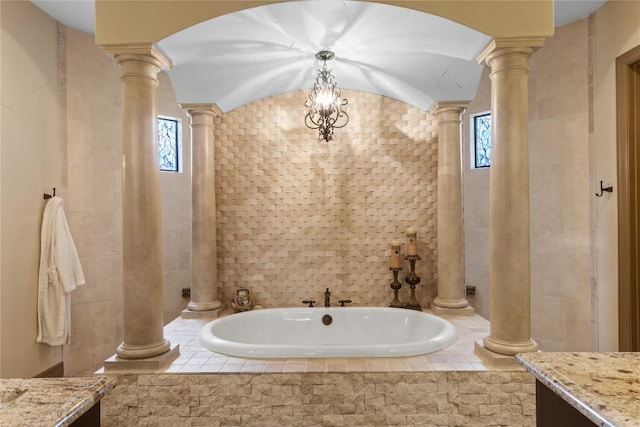 bathroom with ornate columns, a garden tub, tile walls, and vanity