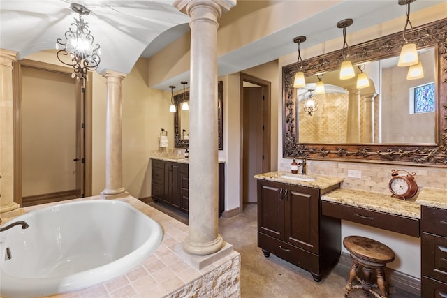 bathroom with vanity, decorative columns, a relaxing tiled tub, and an inviting chandelier