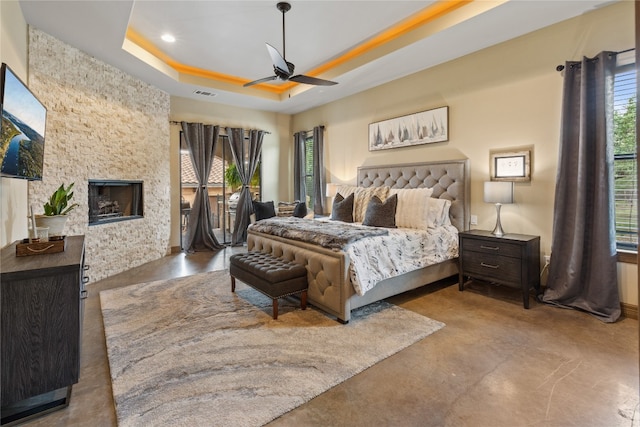 4609 Boxwood Bnd, Lago Vista, TX 78645 - bedroom featuring concrete floors, a raised ceiling, a stone fireplace, recessed lighting, and a ceiling fan