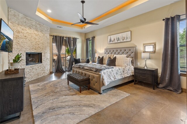 4609 Boxwood Bnd, Lago Vista, TX 78645 - bedroom with concrete floors, a raised ceiling, a stone fireplace, recessed lighting, and a ceiling fan