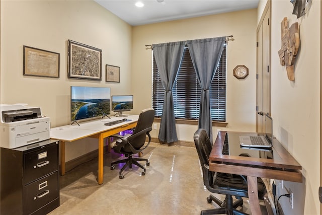 home office featuring concrete floors and baseboards