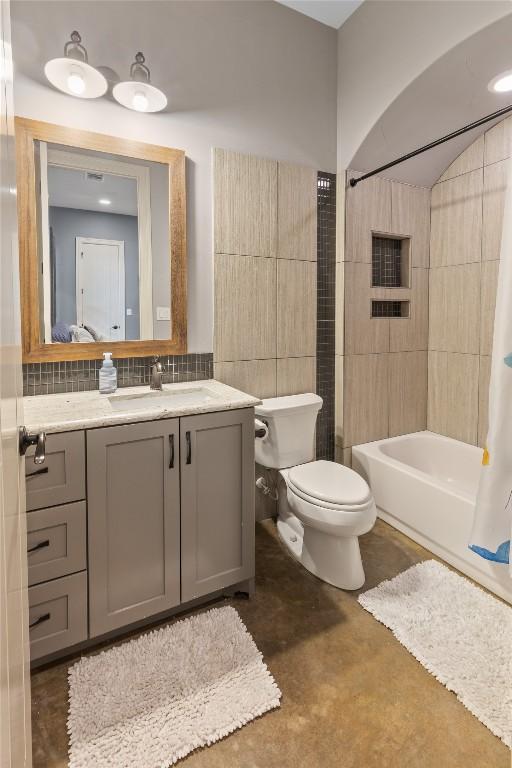 full bathroom featuring toilet, concrete floors, tile walls, vanity, and shower / bath combination with curtain