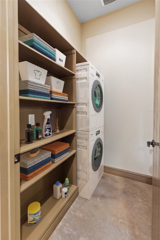 clothes washing area with stacked washing maching and dryer and light colored carpet