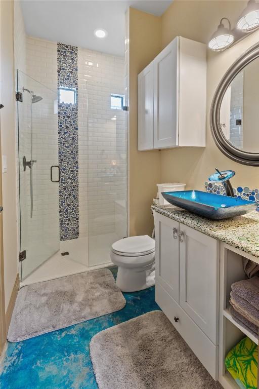 full bathroom featuring toilet, a stall shower, and vanity