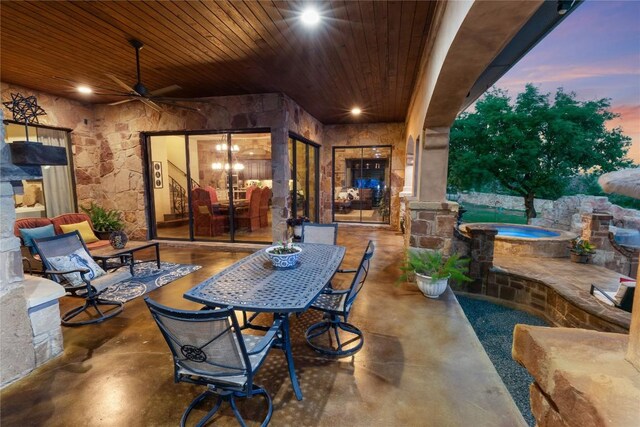 patio terrace at dusk with ceiling fan and an in ground hot tub