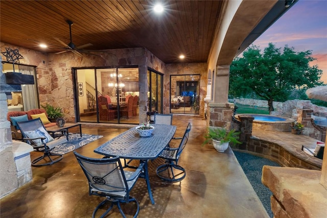 view of patio featuring outdoor dining area, ceiling fan, and an in ground hot tub