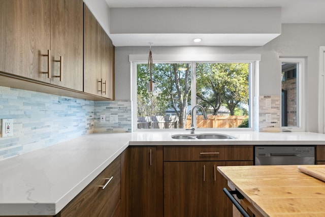 kitchen featuring kitchen peninsula, tasteful backsplash, stainless steel dishwasher, and sink