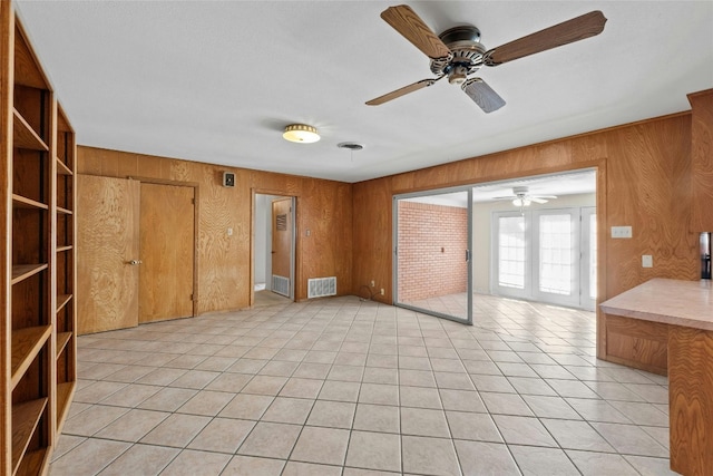 empty room featuring ceiling fan and wooden walls