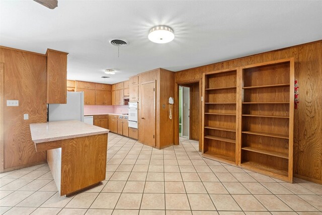 1311 Ridgehaven Dr, Austin, TX 78723 - kitchen featuring white appliances, wood walls, a peninsula, light countertops, and light tile patterned floors
