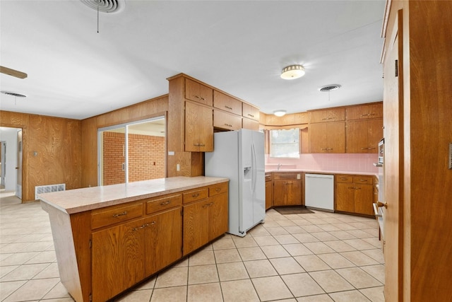 kitchen with kitchen peninsula, decorative backsplash, light tile patterned floors, and white appliances