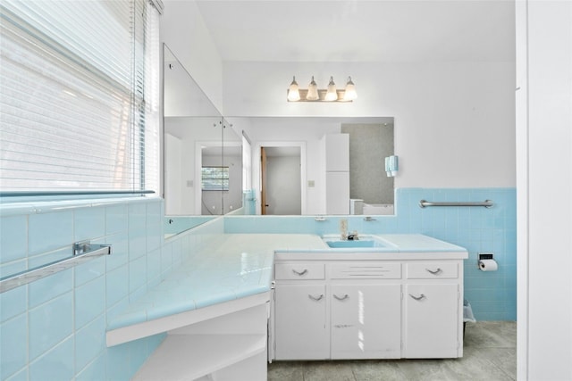 bathroom with tile walls, tile patterned flooring, and vanity