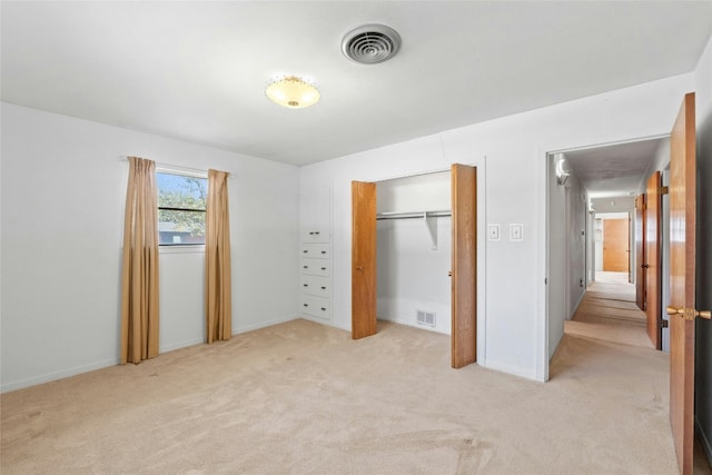 unfurnished bedroom featuring light carpet and a closet