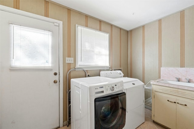 clothes washing area featuring sink, cabinets, a wealth of natural light, and washing machine and clothes dryer