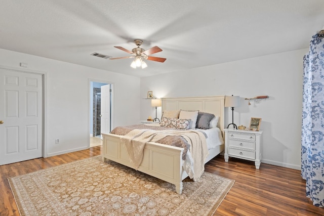 bedroom with ensuite bathroom, a textured ceiling, dark wood-type flooring, and ceiling fan