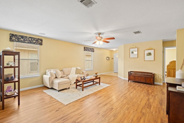 living room with ceiling fan, a textured ceiling, and light hardwood / wood-style floors