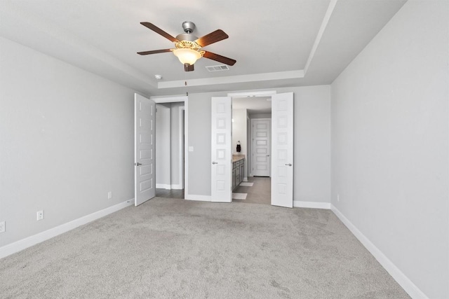 unfurnished bedroom with carpet floors, a raised ceiling, and ceiling fan