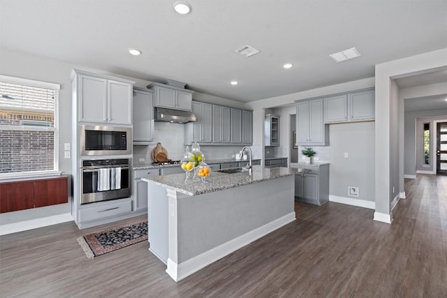 kitchen featuring gray cabinetry, a center island with sink, and appliances with stainless steel finishes