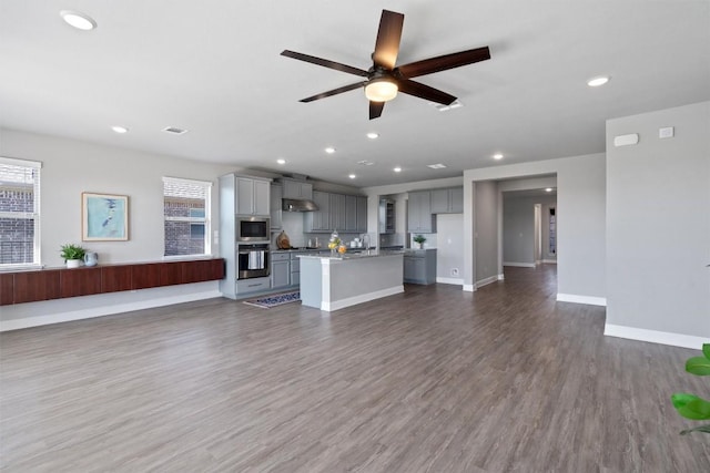 unfurnished living room with dark hardwood / wood-style floors, ceiling fan, and sink