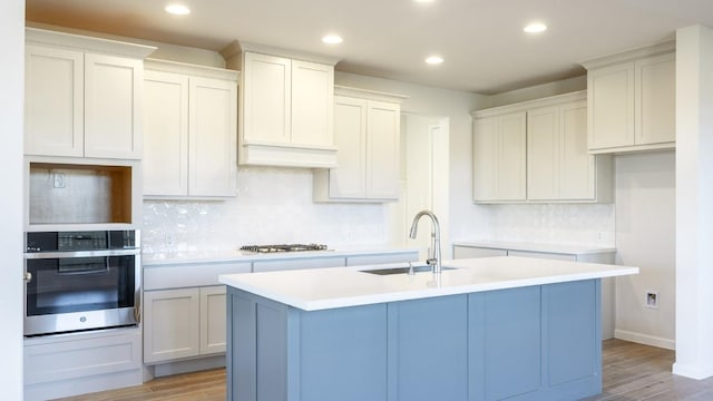 kitchen featuring stainless steel appliances, a center island with sink, and light hardwood / wood-style floors