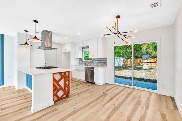 kitchen with pendant lighting, tasteful backsplash, white cabinets, island exhaust hood, and stainless steel dishwasher