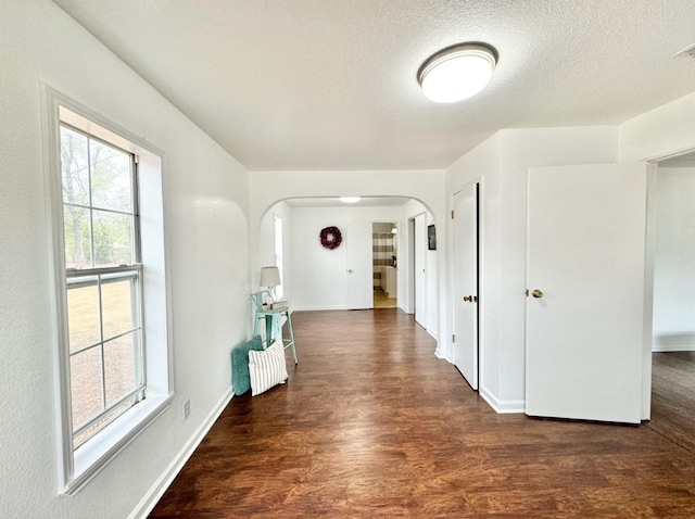 hall featuring dark wood-type flooring and a textured ceiling