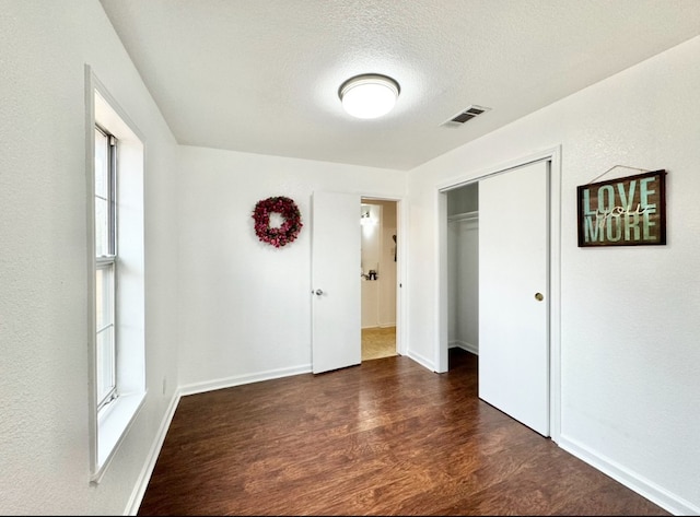 unfurnished room featuring dark hardwood / wood-style flooring and a textured ceiling