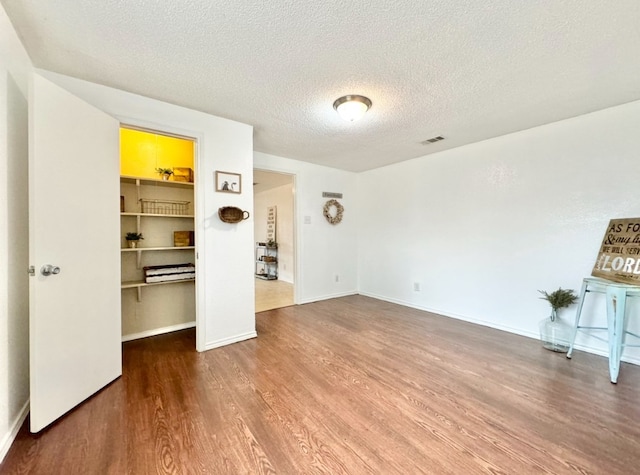 unfurnished living room featuring wood-type flooring and a textured ceiling