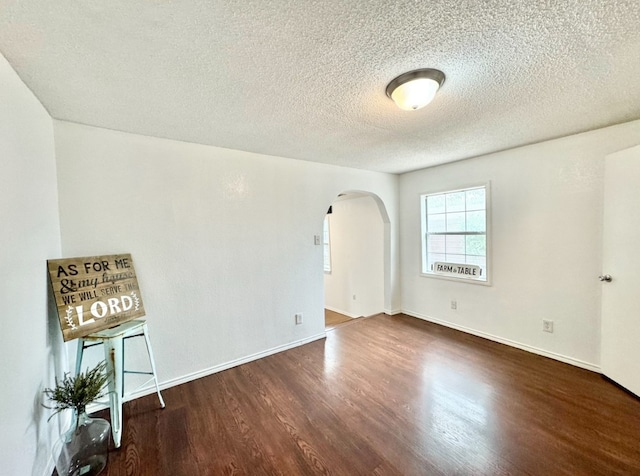 unfurnished room featuring a textured ceiling and dark hardwood / wood-style floors