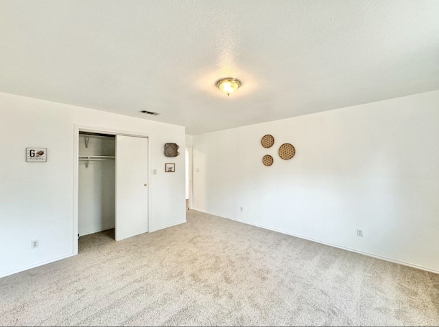 unfurnished bedroom featuring a textured ceiling, a closet, and carpet