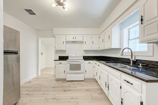 kitchen featuring white electric range oven, stainless steel fridge, white cabinetry, and sink