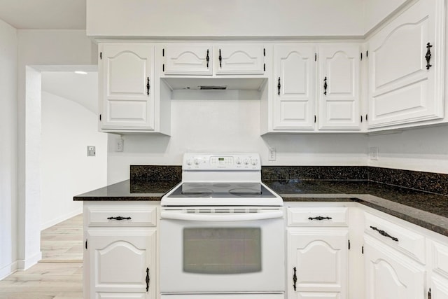 kitchen featuring electric stove, dark stone countertops, white cabinets, and light hardwood / wood-style flooring