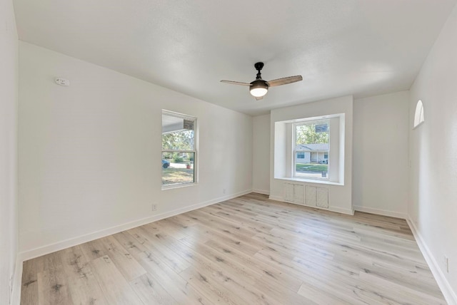 empty room with radiator heating unit, light hardwood / wood-style floors, and ceiling fan