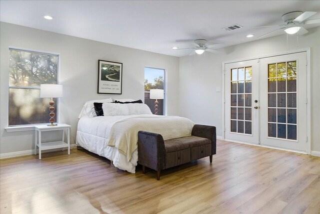 bedroom featuring multiple windows, light hardwood / wood-style flooring, and french doors