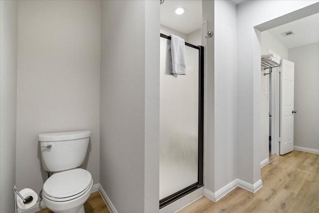 bathroom featuring hardwood / wood-style flooring, a shower with door, and toilet