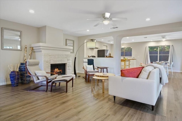 living room featuring ceiling fan, a fireplace, and hardwood / wood-style floors