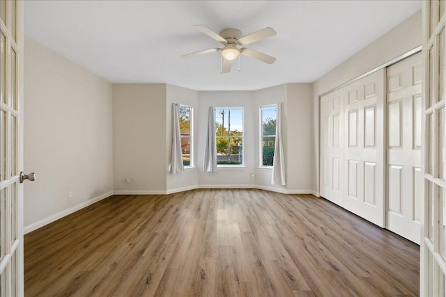 unfurnished bedroom featuring ceiling fan, a closet, light wood-type flooring, and french doors