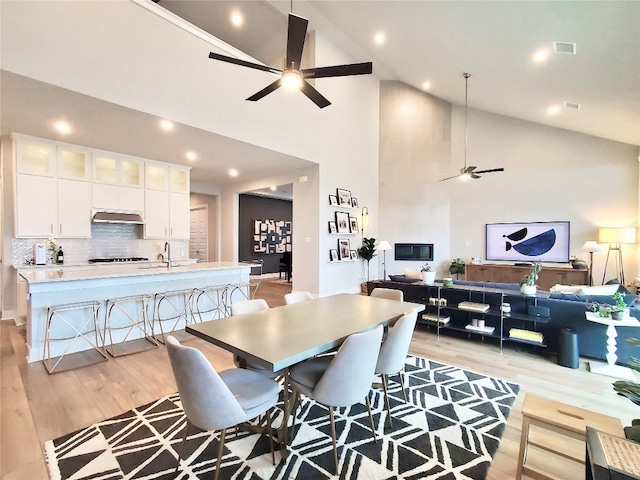 dining area featuring high vaulted ceiling, light hardwood / wood-style floors, ceiling fan, and sink