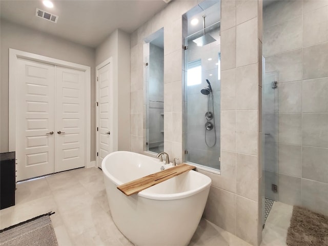 bathroom featuring tile patterned flooring, plus walk in shower, and tile walls