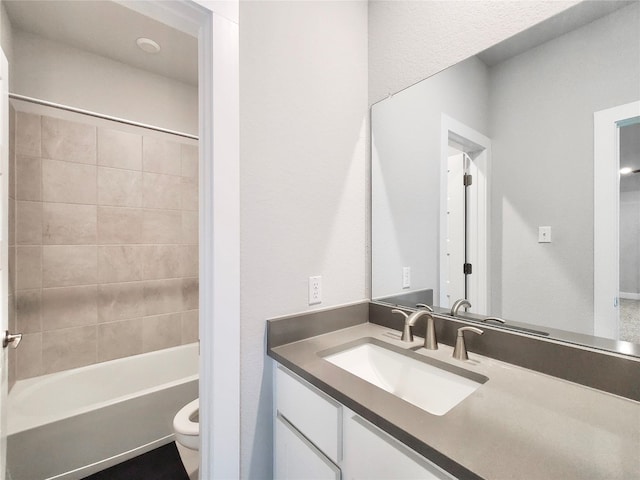 full bathroom featuring tiled shower / bath, toilet, and vanity