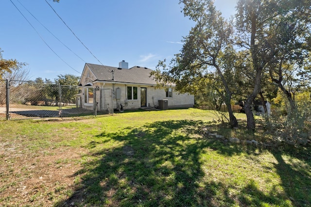 rear view of property featuring central air condition unit and a yard