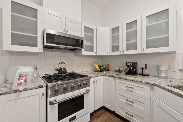 kitchen featuring appliances with stainless steel finishes, tasteful backsplash, white cabinetry, and light stone counters