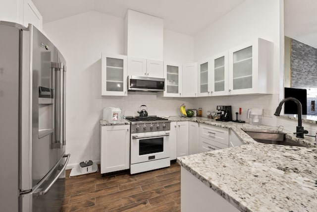 kitchen with light stone countertops, backsplash, stainless steel appliances, sink, and white cabinets