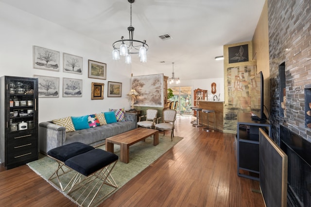 living room with a large fireplace, an inviting chandelier, and dark wood-type flooring